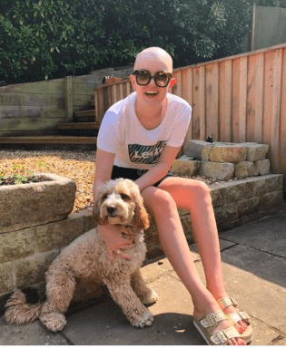 a brave young woman with no wig, sharing her experience of blood cancer, she is sitting in the garden with her dog